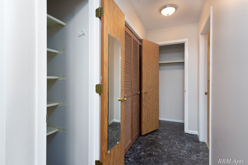 Hallway with dark marble-look floor, shelved closet and wood bifold closet doors, South Slusser apartment 440-6