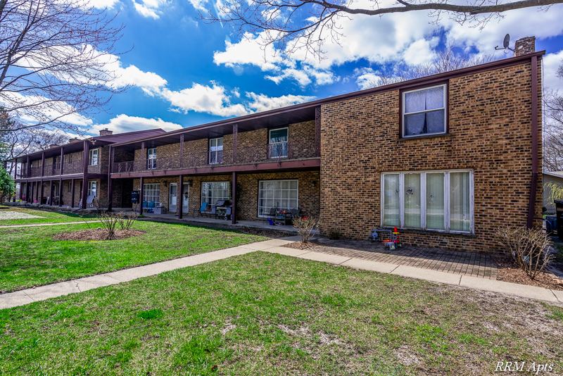 Two-story brick apartment building with second-floor balconies and a front lawn at South Slusser