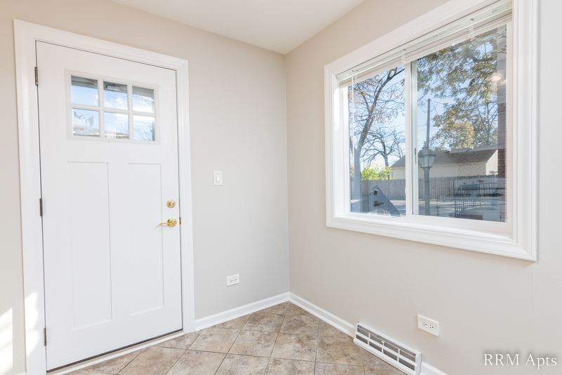 Entry with tile floor, glass-paned white door, window and baseboard radiator, Westerfield Place apartment 143 B