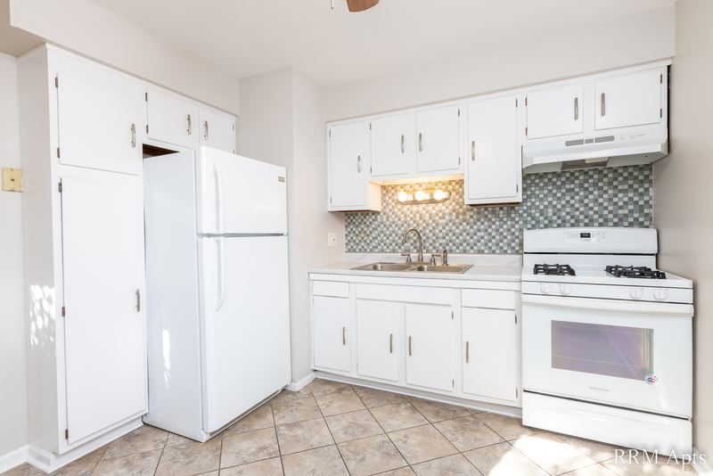 Kitchen with white cabinets, white refrigerator, gas stove and gray tile backsplash, Westerfield Place apartment 143 B