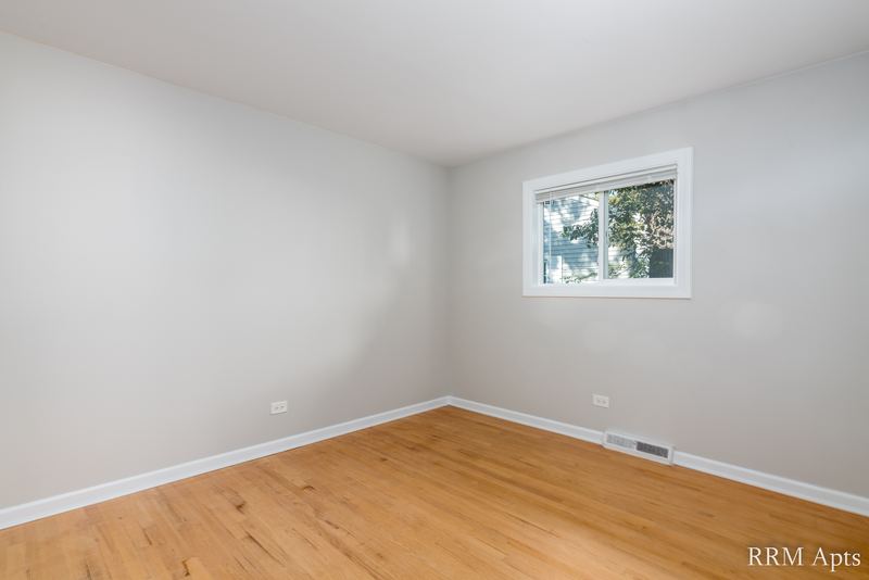 Bedroom with wood floor, gray walls and single window facing trees, Westerfield Place apartment 143 B