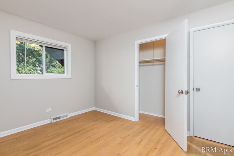 Bedroom with wood floor, window, open closet with shelf and white door, Westerfield Place apartment 143 B