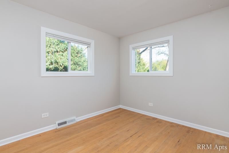 Bedroom with wood floor, gray walls and two windows facing trees, Westerfield Place apartment 143 B