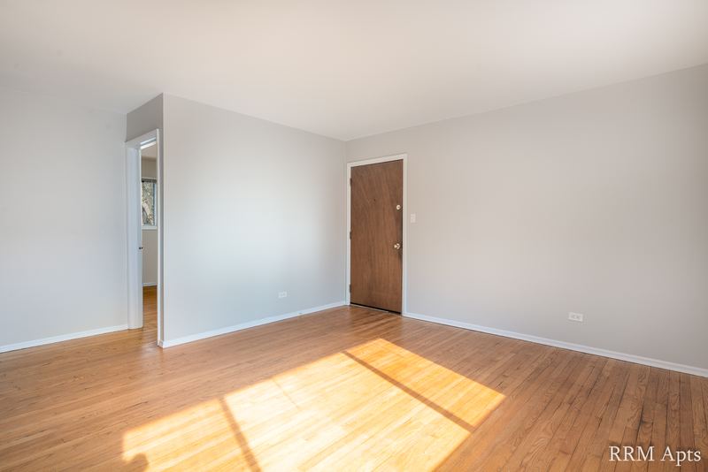 Living room with wood floor, wood entry door and doorway to the hall, Westerfield Place apartment 143 C