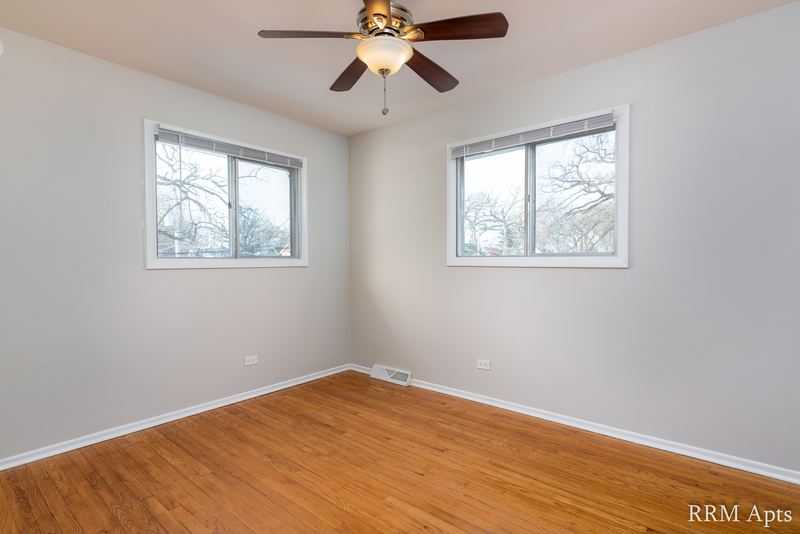Bedroom with wood floor, ceiling fan and two windows facing trees, Westerfield Place apartment 143 C