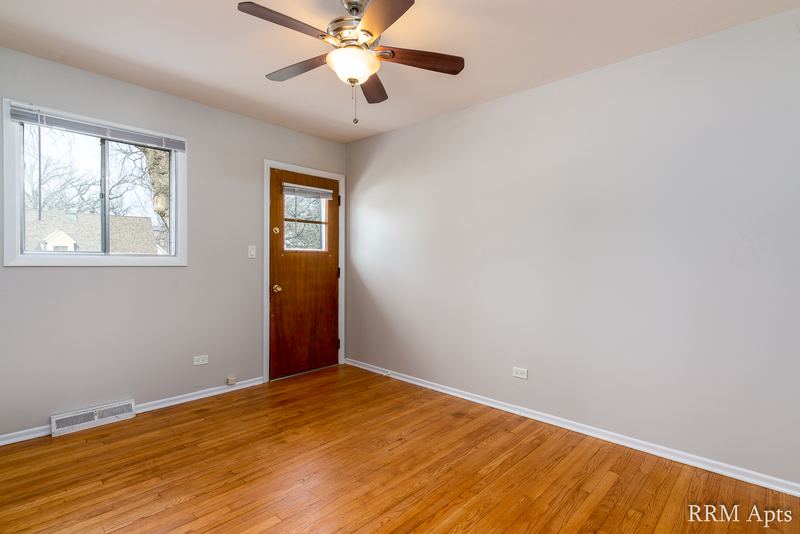 Bedroom with wood floor, ceiling fan, window and wood entry door, Westerfield Place apartment 143 C