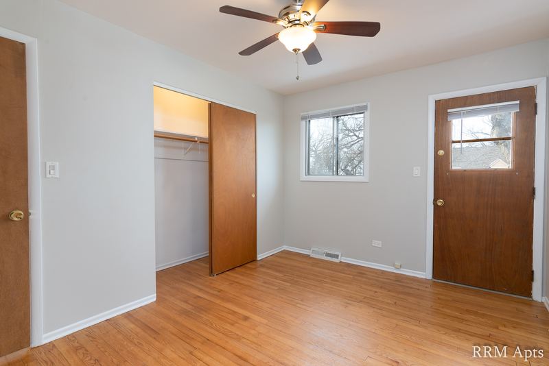 Bedroom with wood floor, ceiling fan, open wood-door closet, window and wood door, Westerfield Place apartment 143 C