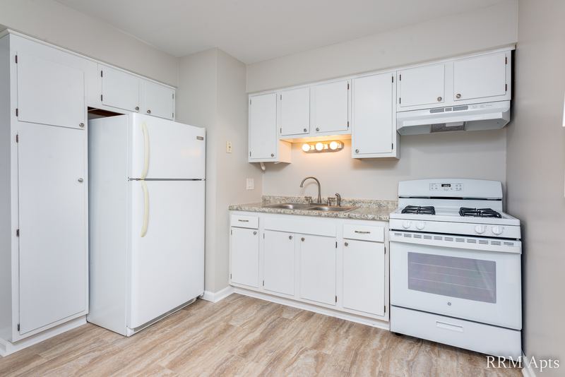 Kitchen with white cabinets, white refrigerator, gas stove and range hood, Westerfield Place apartment 143 D