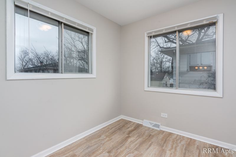 Dining area with wood-look floor and two windows facing trees, Westerfield Place apartment 143 D