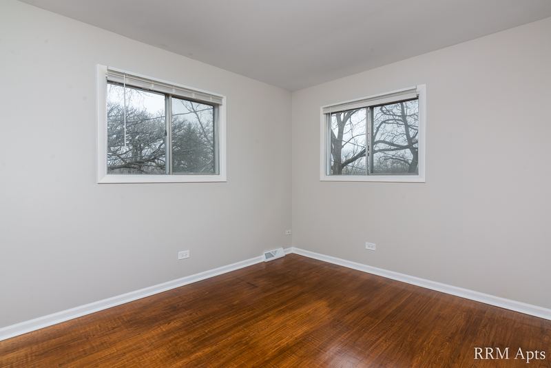 Bedroom with wood floor, gray walls and two windows facing trees, Westerfield Place apartment 143 D