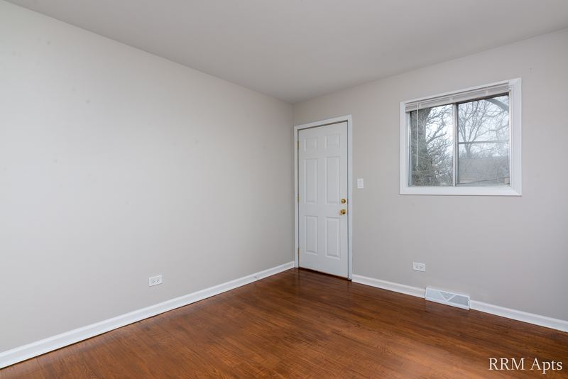 Bedroom with wood floor, white door and single window facing trees, Westerfield Place apartment 143 D