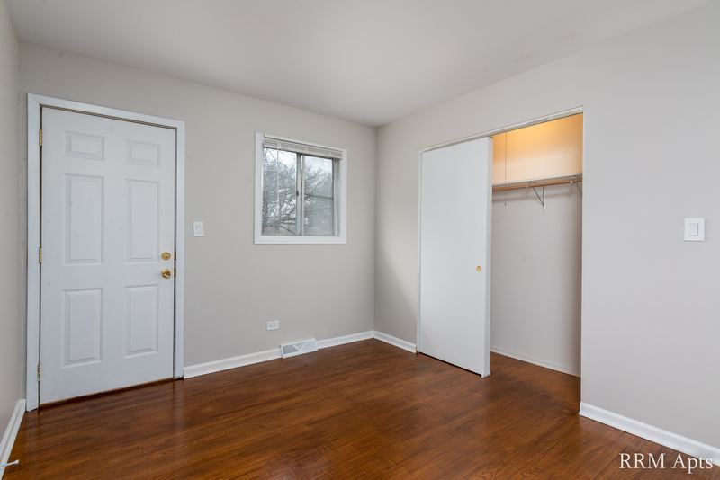 Bedroom with wood floor, white entry door, window and open closet with shelf, Westerfield Place apartment 143 D