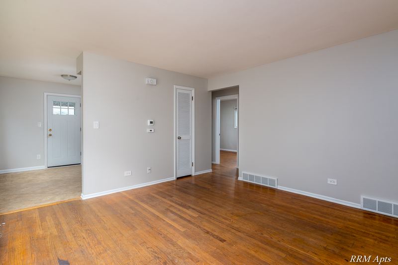 Living room with wood floor, glass-paned white entry door and doorway to the hall, Westerfield Place apartment 143A