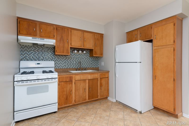 Kitchen with oak cabinets, white gas stove, white refrigerator and gray tile backsplash, Westerfield Place apartment 143A