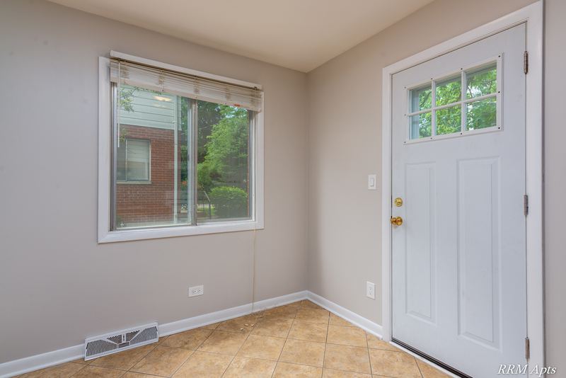 Entry with tile floor, glass-paned white door and window facing a brick building, Westerfield Place apartment 143A