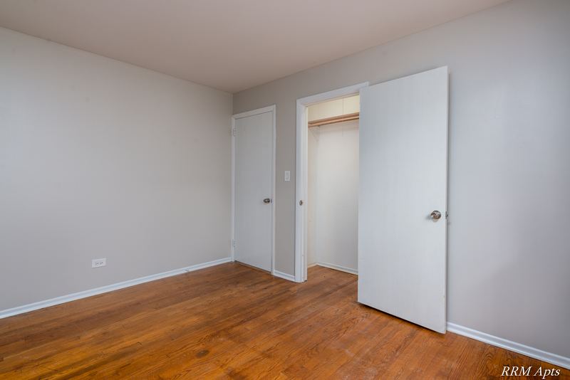 Bedroom with wood floor, open closet with white door and white entry door, Westerfield Place apartment 143A