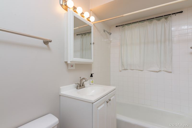 Bathroom with white vanity, medicine cabinet, towel bar and white tub with shower curtain, Westerfield Place apartment 143A