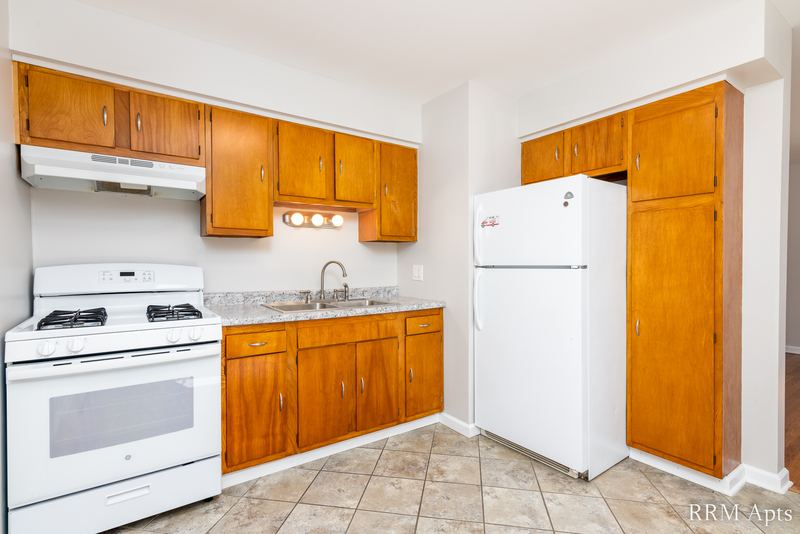 Kitchen with oak cabinets, white gas stove, white refrigerator and beige tile floor, Westerfield Place apartment 145A