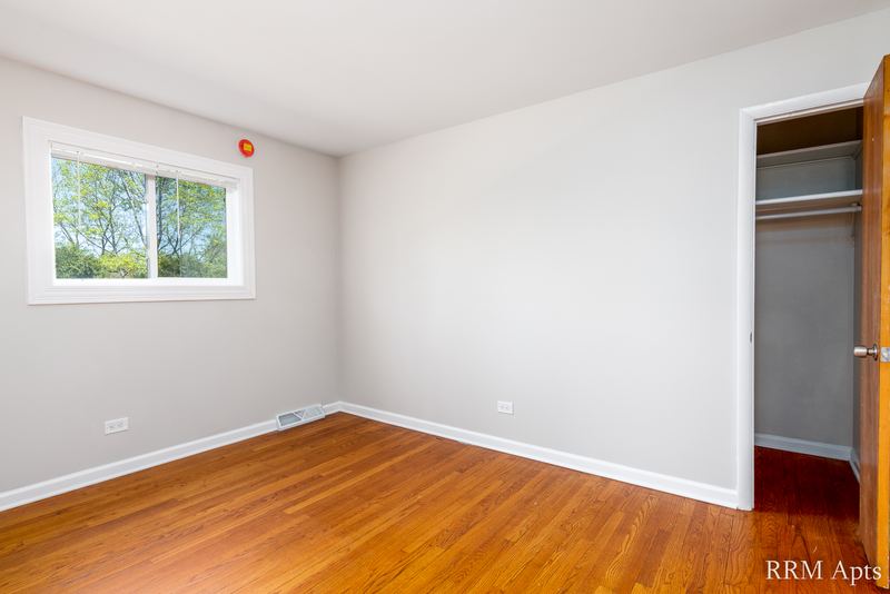 Bedroom with wood floor, window, open closet with hanging rod and baseboard radiator, Westerfield Place apartment 145A
