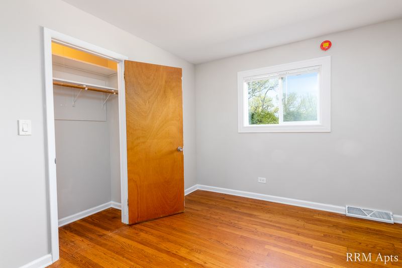 Bedroom with wood floor, window and open closet with wood door and shelf, Westerfield Place apartment 145A