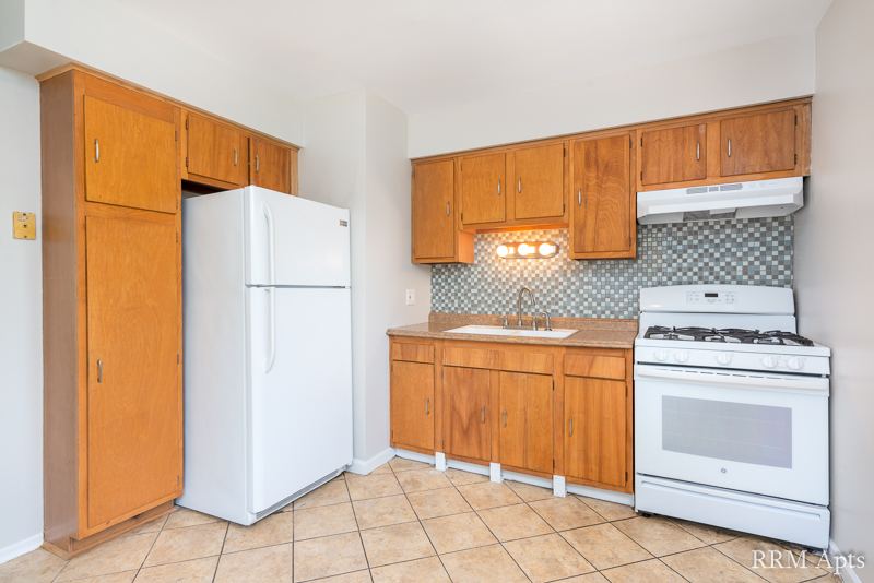 Kitchen with oak cabinets, white refrigerator and gas stove and tile backsplash, Westerfield Place apartment 145D