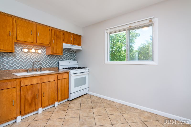 Kitchen with oak cabinets, sink under a window and white gas stove, Westerfield Place apartment 145D