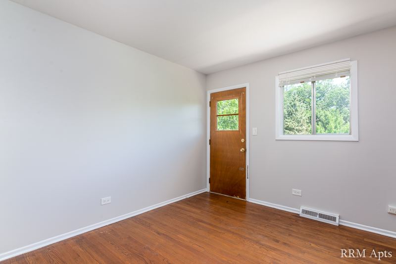 Bedroom with hardwood floor, window and wood entry door, Westerfield Place apartment 145D