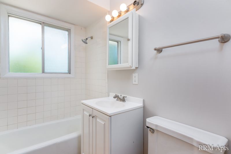 Bathroom with white vanity, medicine cabinet, tiled tub and frosted window, Westerfield Place apartment 145D
