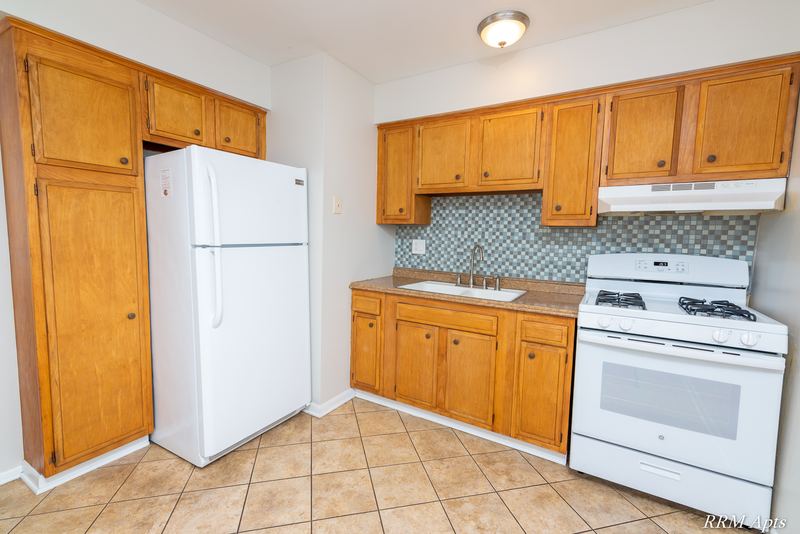 Kitchen with oak cabinets, white refrigerator, gas stove and gray tile backsplash, Westerfield Place apartment 147 C