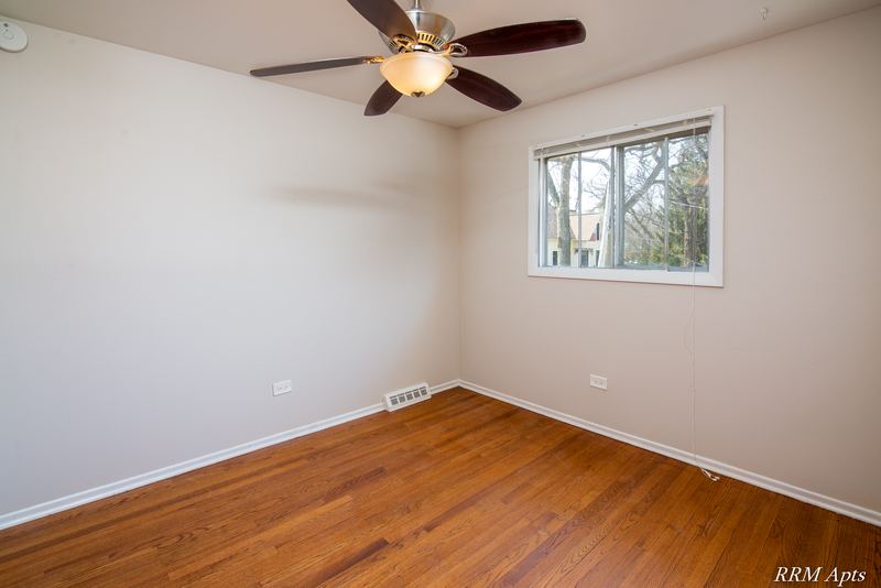 Bedroom with wood floor, ceiling fan, single window facing trees and baseboard radiator, Westerfield Place apartment 147 C