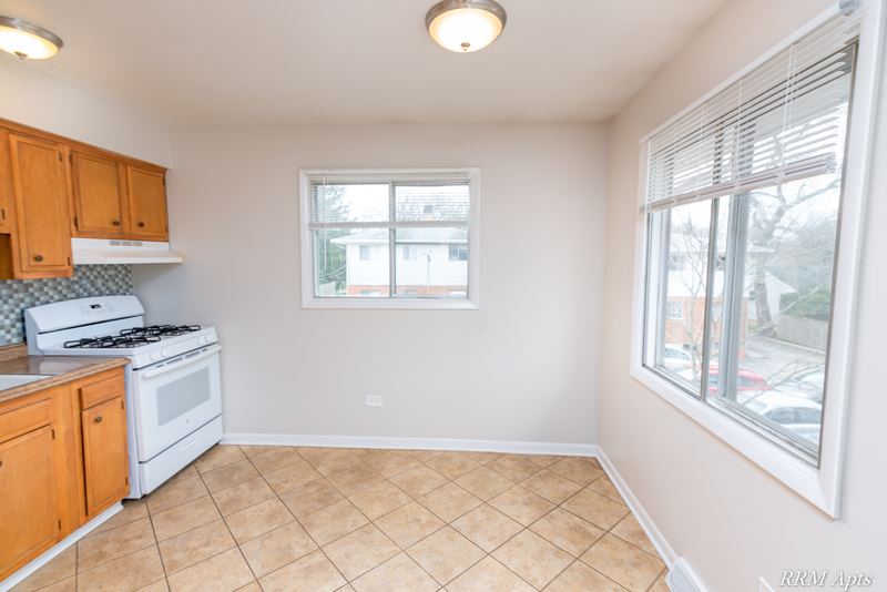 Kitchen with oak cabinets, white gas stove, beige tile floor and two windows, Westerfield Place apartment 147 C
