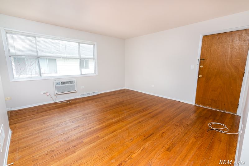 Living room with wood floor, window, wall air conditioner and wood entry door, Westerfield Place apartment 147 C