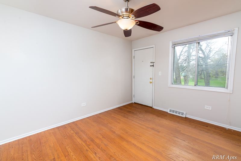 Bedroom with wood floor, ceiling fan, white door and window facing trees, Westerfield Place apartment 147 C