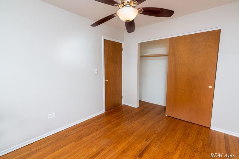 Bedroom with wood floor, ceiling fan, open wood closet door and wood entry door, Westerfield Place apartment 147 C