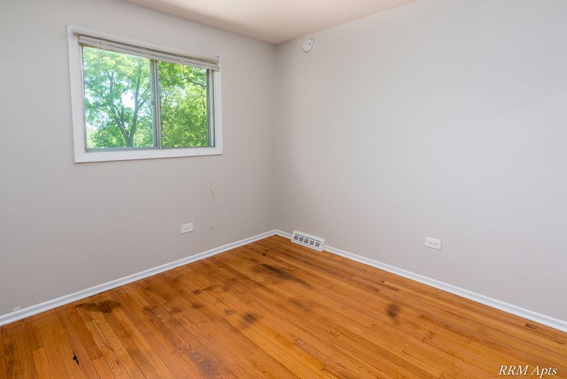 Bedroom with wood floor, single window facing trees and baseboard radiator, Westerfield Place apartment 147 D