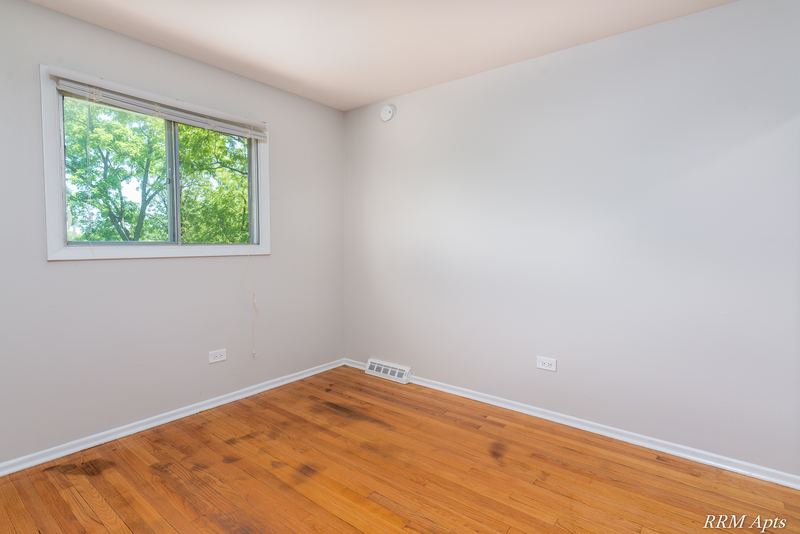 Bedroom with wood floor, gray walls and single window facing trees, Westerfield Place apartment 147 D