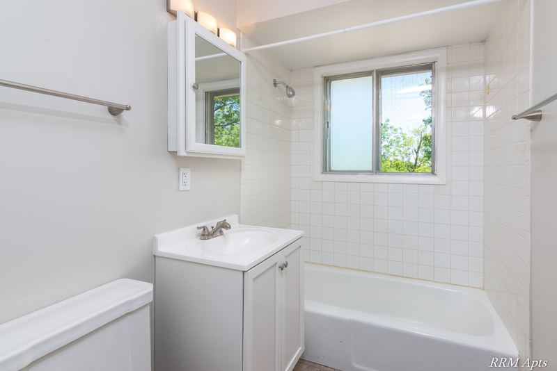Bathroom with white vanity, medicine cabinet, window and white tile tub surround, Westerfield Place apartment 147 D