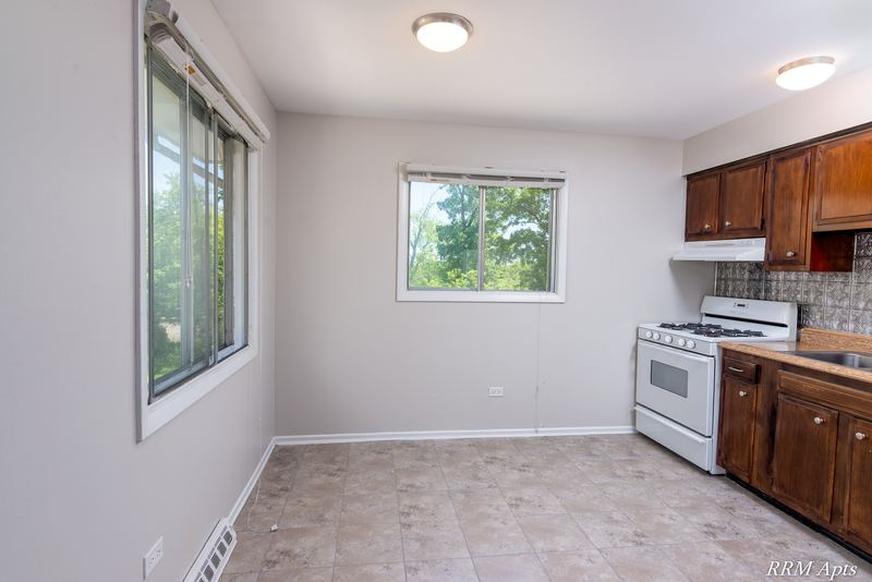 Kitchen with dark wood cabinets, white gas stove, two windows and beige tile floor, Westerfield Place apartment 147 D