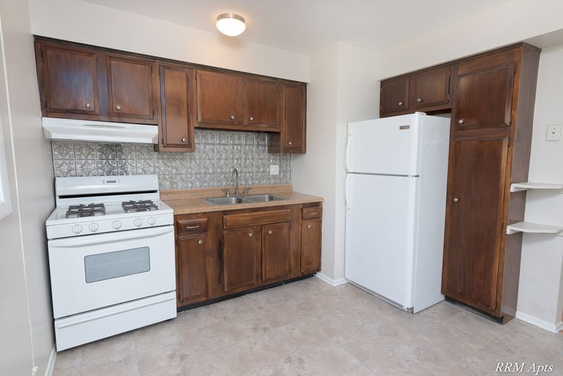 Kitchen with dark wood cabinets, white gas stove, white refrigerator and tile backsplash, Westerfield Place apartment 147 D