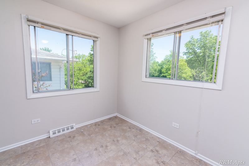 Dining area with beige tile floor and two windows facing trees and houses, Westerfield Place apartment 147 D