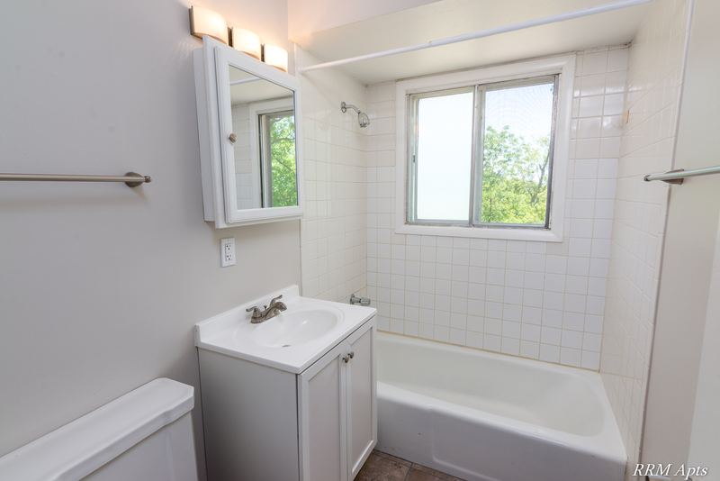 Bathroom with white vanity, medicine cabinet, towel bar and white tile tub surround, Westerfield Place apartment 147 D