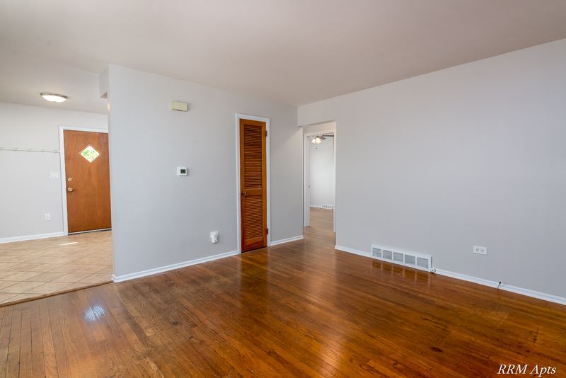 Living room with wood floor, wood doors, baseboard radiator and doorway to the kitchen, Westerfield Place apartment 147B
