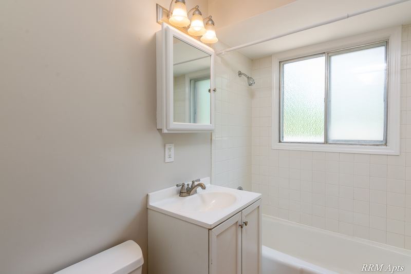 Bathroom with white vanity, medicine cabinet, frosted window and white tile tub surround, Westerfield Place apartment 147B