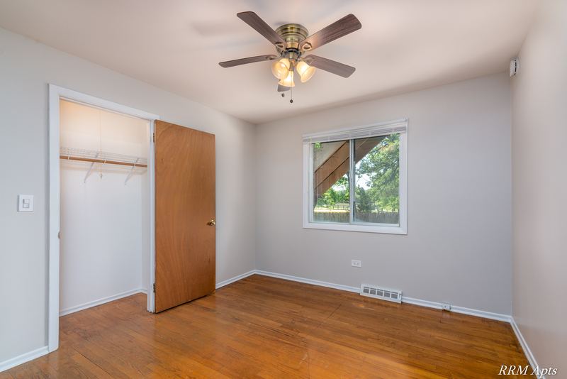 Bedroom with wood floor, ceiling fan, open wood sliding-door closet and window, Westerfield Place apartment 147B