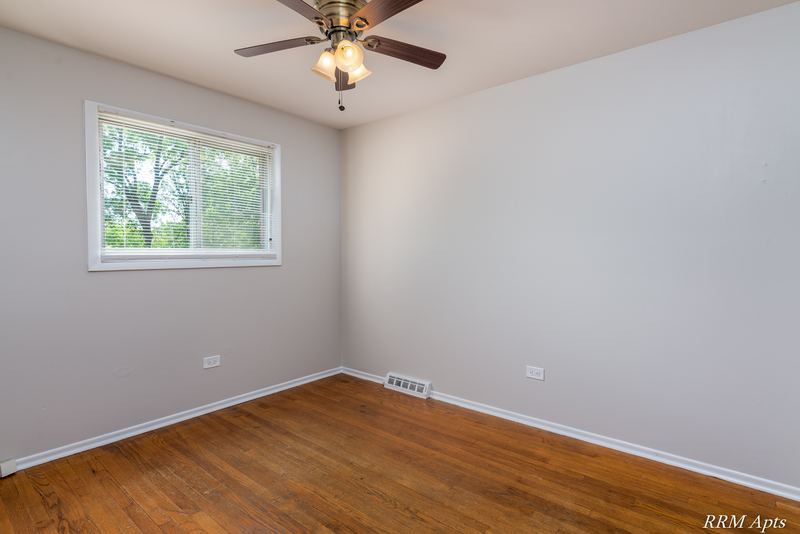 Bedroom with wood floor, ceiling fan, gray walls and window facing trees, Westerfield Place apartment 147B