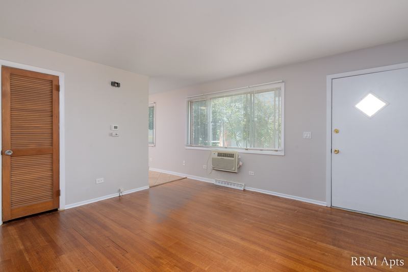 Living room with wood floor, wall air conditioner and white door with diamond window, Westerfield Place apartment 149 A