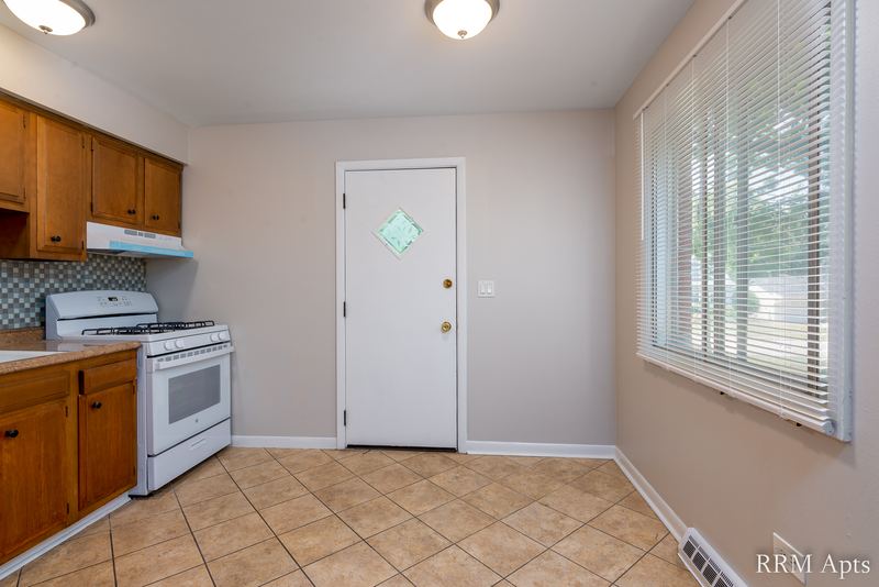 Kitchen with oak cabinets, white gas stove, tile floor, white back door and window, Westerfield Place apartment 149 A