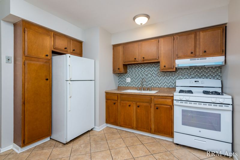 Kitchen with oak cabinets, white refrigerator, white gas stove and patterned backsplash, Westerfield Place apartment 149 A