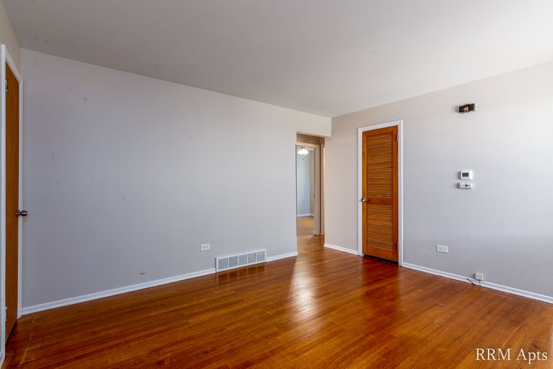 Living room with wood floor, hallway to bedrooms and a wood door on the right, Westerfield Place apartment 149 A