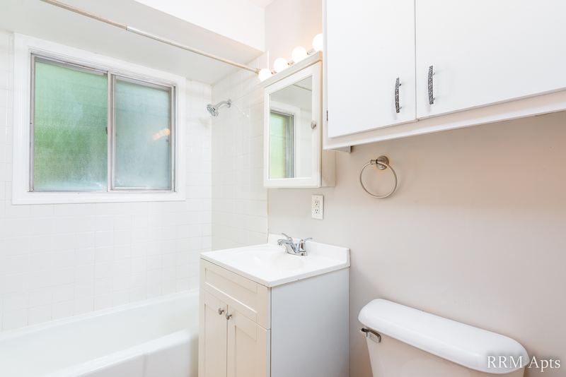 Bathroom with white tub, frosted window, white vanity, mirror and wall cabinet, Westerfield Place apartment 149 A